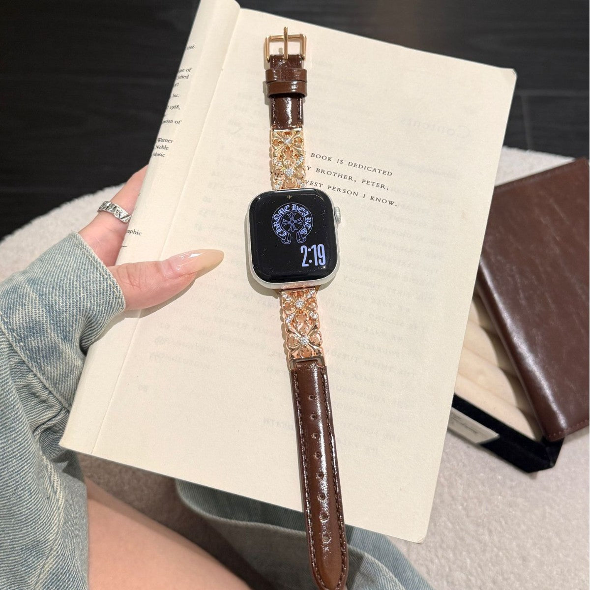 Brown Dreamy Flower leather band with Apple Watch laid over a notebook