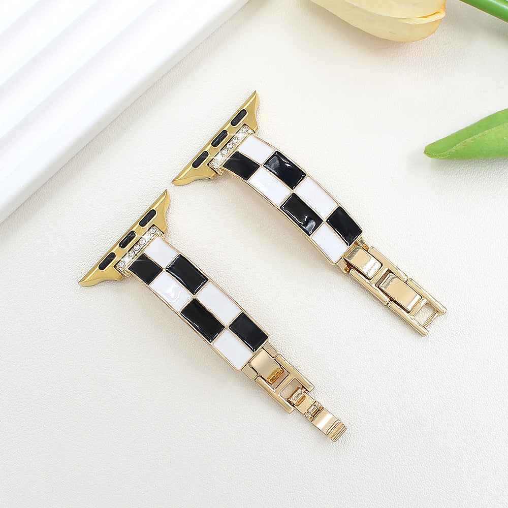 Black and white checkerboard band with warm metal finish, flat lay
